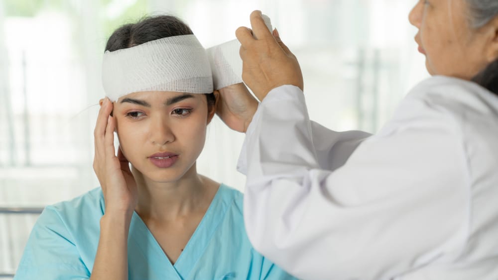 a female doctor bandaging an Asian woman's head because of her head injuries